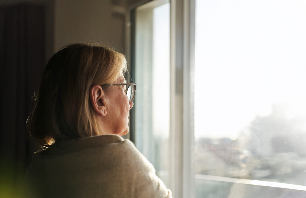 Caucasian senior woman with depression looking throw the window